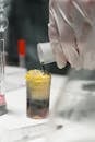 Person Pouring Yellow Liquid on Clear Drinking Glass